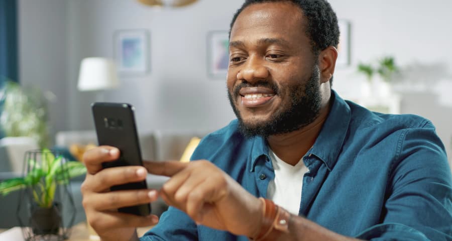 Man in his home interacting with an app on his cell phone